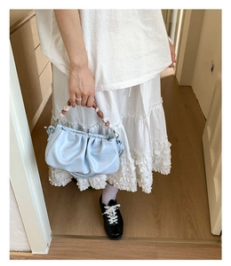 Detail of light blue pleated cloud bag featuring brown marble-textured beaded handle