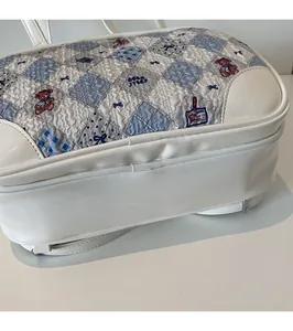 Detailed side view of white leather tote bag featuring quilted bear story pattern texture