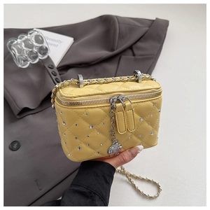 Detail of yellow quilted box bag featuring sparkling rhinestones and silver rose charm