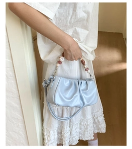 Detail of light blue ruched cloud bag featuring decorative marble-patterned bead handles