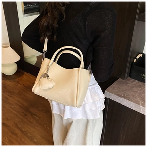 Detail of cream lychee texture leather handbag with heart charm and detachable strap