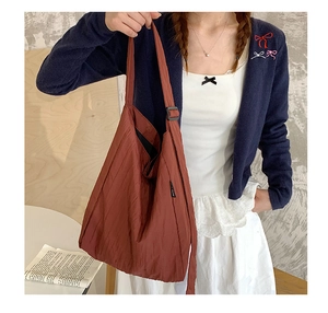 Dettaglio della borsa tote in nylon rosso mattone con tracolla e trama a pieghe