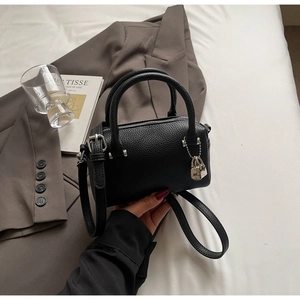 Detail of black lychee grain leather mini Boston bag with silver hardware and charms