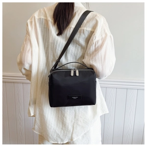 Détail d'un sac bandoulière en nylon noir avec doubles fermetures éclair argentées