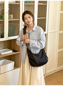 Detail of black dumpling hobo bag with white heart embroidery on a casual outfit