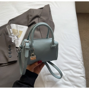 Detail of light blue pebble leather boston bag with silver lock and double handles
