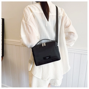 Détail d'une femme portant le sac à bandoulière en nylon noir au style minimaliste