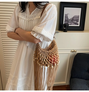 Macro detail of beige woven macrame shoulder bag with fringe tassels and pearl beads