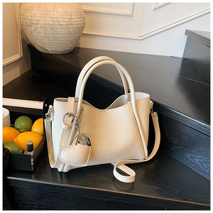 Close-up of cream pebble leather bucket bag with heart charm on a wooden staircase