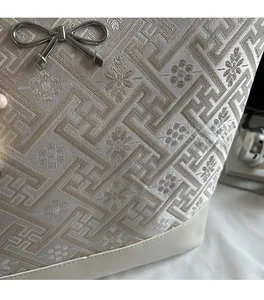 Detailed close-up of woven fabric pattern and metallic bow buckle on the tote bag