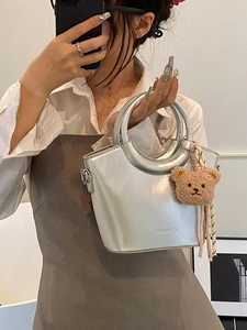 Silver metallic bucket bag with round handle and cute bear charm held by model