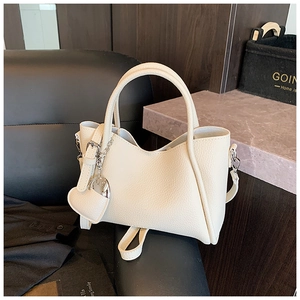 Detail of cream white bucket bag with lychee grain leather and silver heart charm