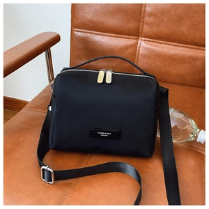 Détail d'un sac bandoulière en nylon noir avec fermetures éclair argentées et poignée