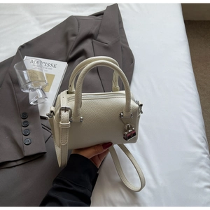 Detail of off-white lychee texture leather handbag with silver lock and shoulder strap