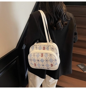 Detail view of cream tote bag featuring cute red bear embroidery and blue quilted fabric