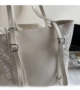 Detail of beige tote bag showing mixed leather fabric texture and silver metal hardware