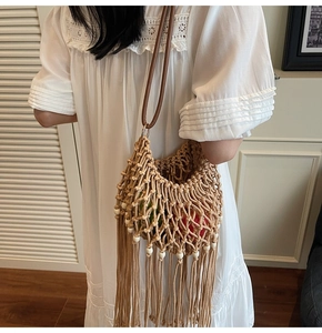 Detail of hand-woven mesh bag featuring bohemian tassels and white wooden beads