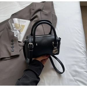 Detail of black pebbled leather Boston bag with silver lock charm and top handles
