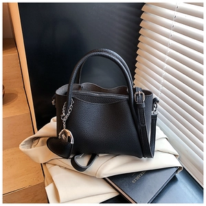 Detail of black lychee grain leather bucket bag with silver heart pendant and strap