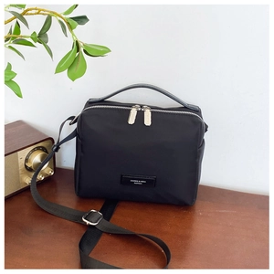 Détail d'un sac bandoulière en nylon noir avec doubles fermetures éclair argentées