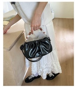 Detail of black pleated cloud bag featuring marble beads and leather texture