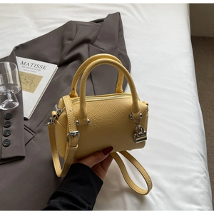 Macro detail of yellow pebbled leather Boston bag with silver lock charm and hardware