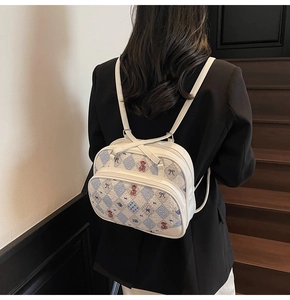 Detail view of white leather backpack with cartoon bear print and checkered front pocket