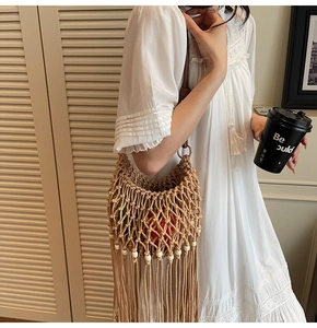 Close-up of woven shoulder bag featuring bohemian tassels and decorative wooden beads