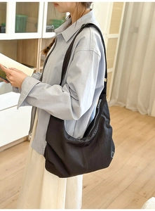 Close-up of a crescent nylon crossbody bag with adjustable wide shoulder strap on a model