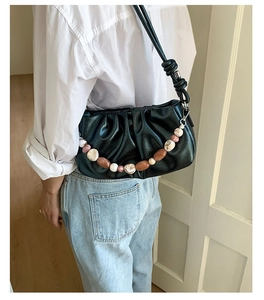 Detail of black pleated cloud bag with marble resin chain and knotted shoulder strap