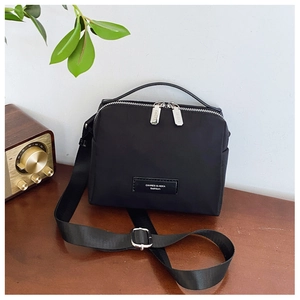 Détail du sac bandoulière en nylon noir avec doubles zips et bandoulière amovible