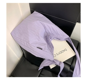 Dettaglio della borsa tote lilla in tela trapuntata con texture a righe e nodo