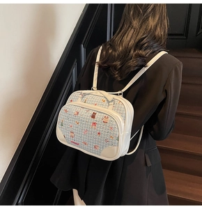 Detail of light blue tweed tote bag with cartoon embroidery and white leather straps
