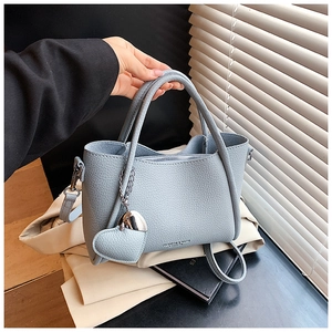Detail of light blue litchi pattern leather bag with heart pendant and metal chain