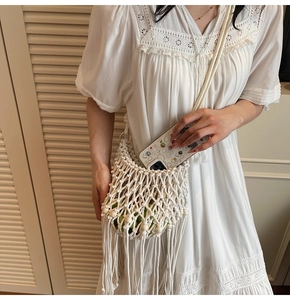 Detail of white woven crochet bag with tassels and beads for summer beach vacations