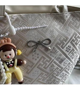 Detail of jacquard tote bag with traditional pattern, bow metal buckle and pearl charm