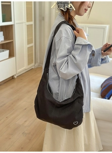 Detail shot of black hobo bag showing the white heart embroidery and canvas texture