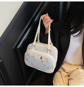Close-up of blue tweed tote bag featuring cartoon bear embroidery and white leather straps