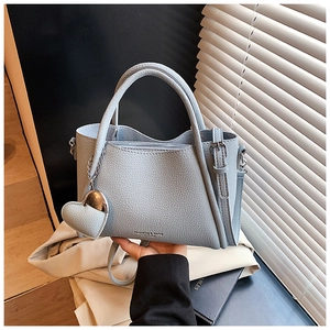 Light blue-grey grainy leather handbag with heart pendant and Fashion & Bags text