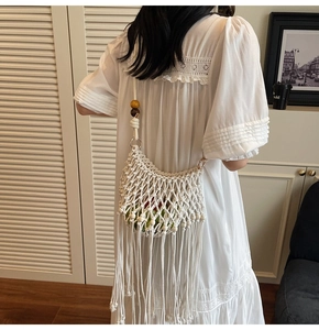 Rear view of a white macrame woven shoulder bag with wooden beads and long tassels