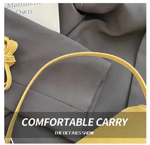 Macro shot of yellow lychee grain leather handbag showing handle attachment detail