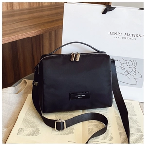 Détail d'un sac à bandoulière en nylon noir avec double fermeture éclair et métal argent