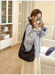 Detailed view of dark brown canvas crescent bag with a minimalist white heart logo