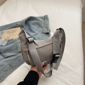 Detail view of grey nylon messenger bag with wide strap and large buckle closure
