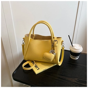 Detail of yellow lychee leather handbag with heart charm and detachable shoulder strap