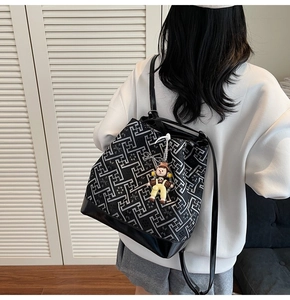 Detailed view of black tote bag with gray geometric pattern and small doll charm accessory
