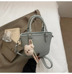 Detail of mint green lychee pattern leather bucket bag with a cute plush bear charm