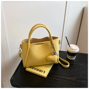 Detailed macro view of yellow pebble leather handbag with gold heart-shaped metal charm