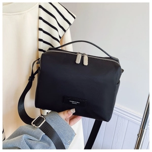 Détail du sac bandoulière en nylon noir avec double zip argenté et bandoulière réglable
