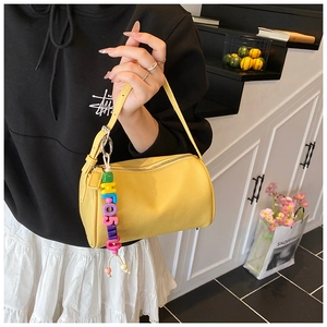 Detail of yellow cylinder bag with lychee texture and colorful beaded charm